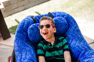 Child seated and supported in a blue P Pod positioning seat