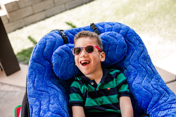 Child seated and supported in a blue P Pod positioning seat